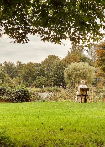 Eine Frau sitzt entspannt an einem See nach einer Yogastunde bei einem Vivere Vital Retreat