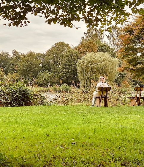 Eine Frau sitzt entspannt an einem See waehrend eines Yoga Retreats mit Vivere Vital