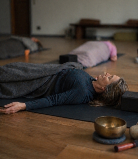 Eine Gruppe lauscht tibetischen Klangschalen in Shavasana waehrend eines Vivere Vital Retreats