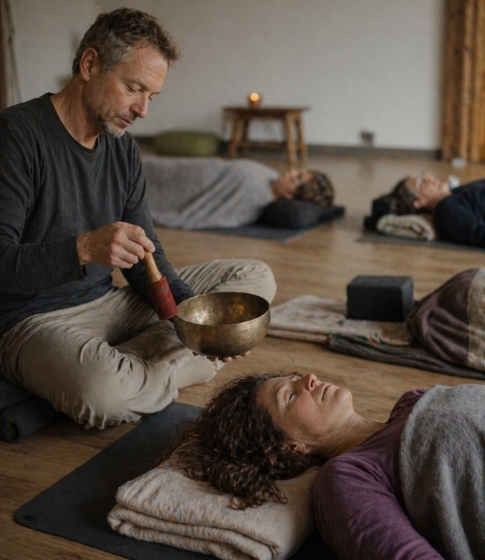 Ein Seminarleiter spielt seine Klangschalen an waehrend eines Klangschalen und Yoga Retreats